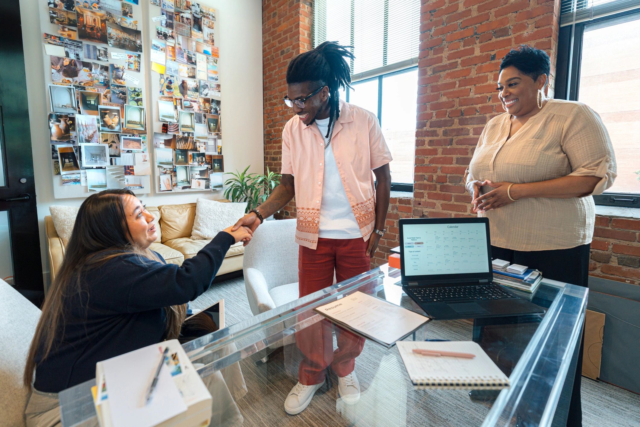 Cheerful Hiring Manager Woman Introducing a Job Interviewee Applicant to a Hispanic / Latino Human Resources Woman in a Comfortable Business Office Setting